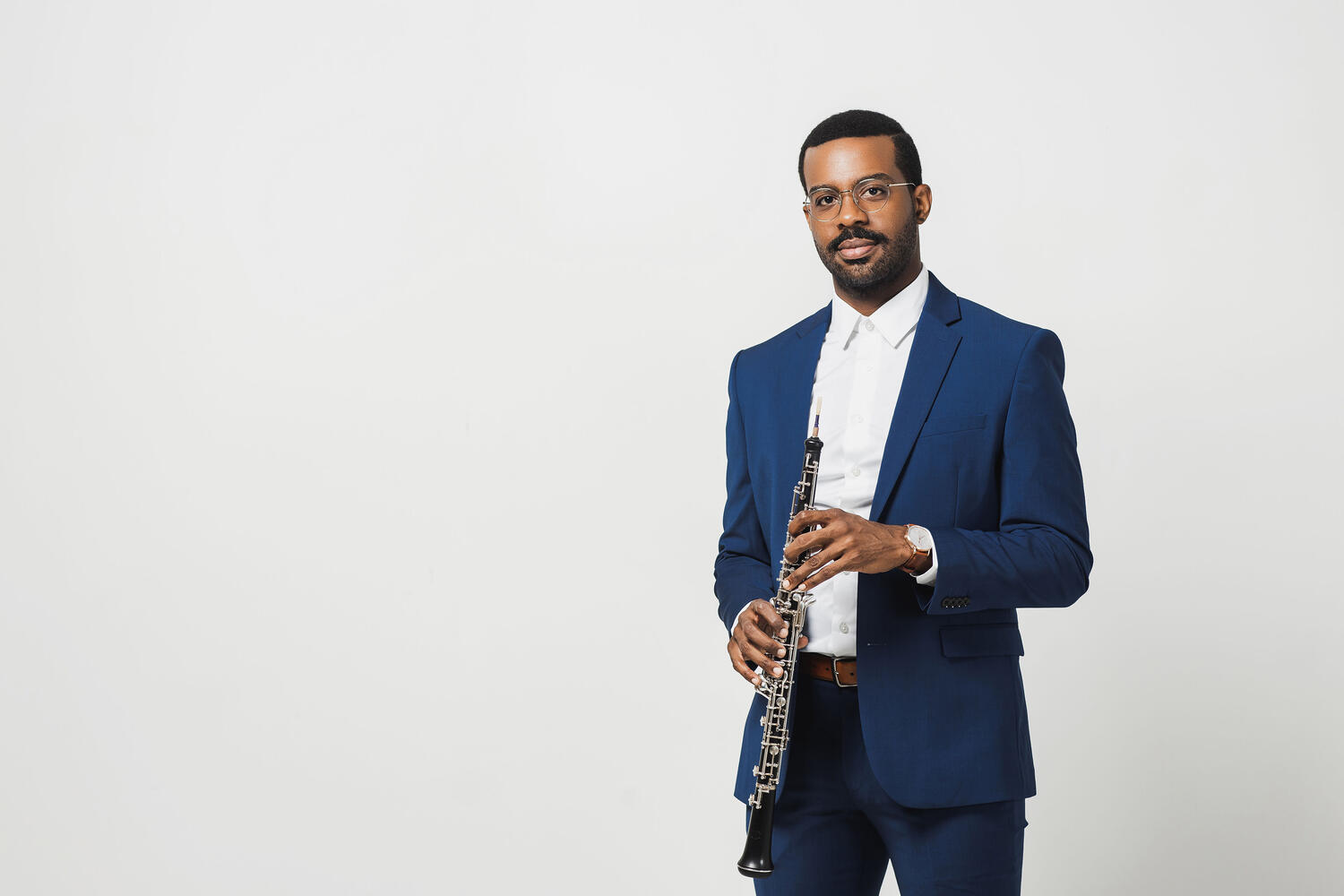 Titus Underwood wearing a blue suit, holding an oboe